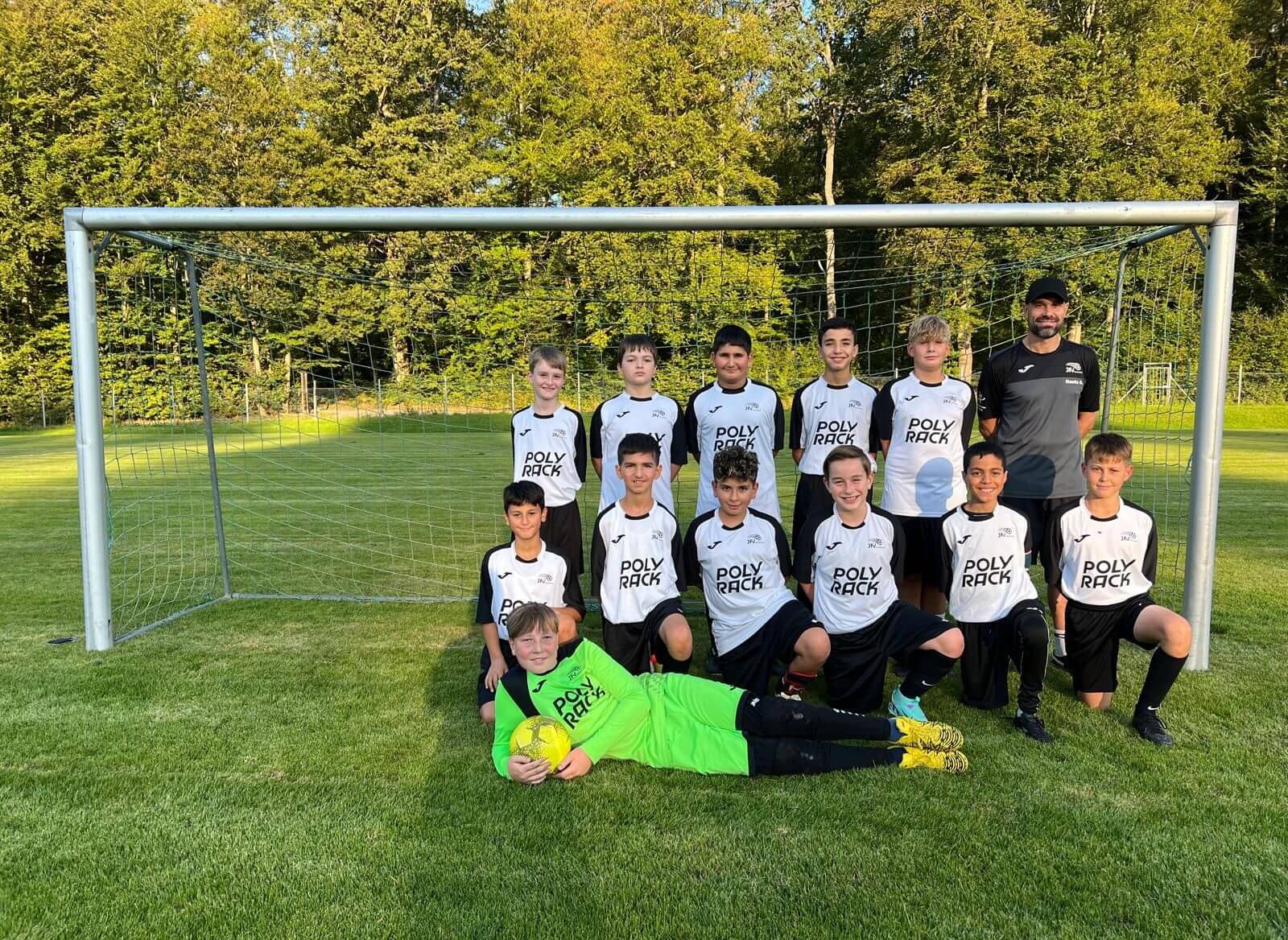 Die Spieler einer Fußballmannschaft stehen vor dem Tor und lächeln für ein Foto.