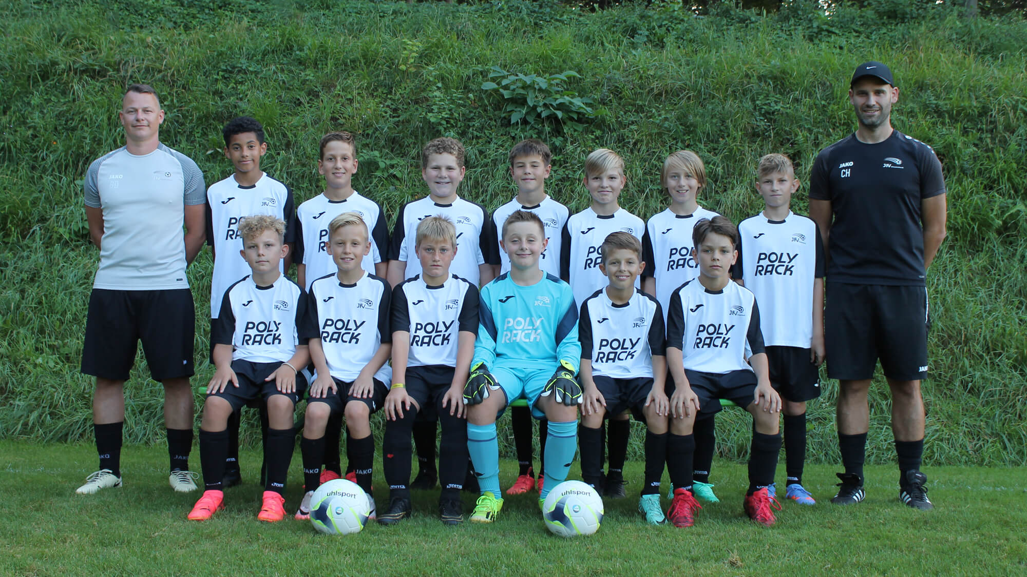 Teamfoto einer Fußballmannschaft, alle Spieler stehen zusammen und lächeln in die Kamera.