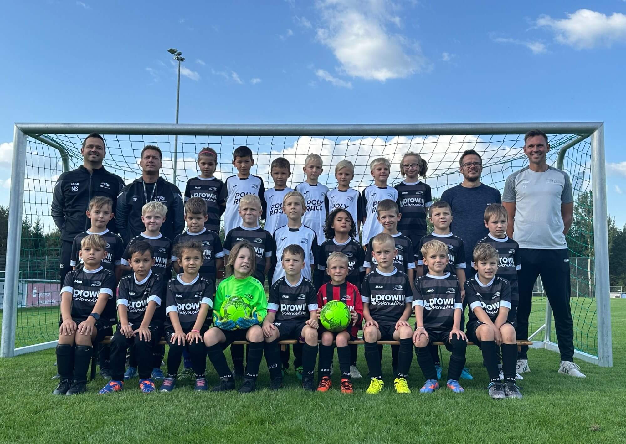 Die Spieler einer Fußballmannschaft stehen vor dem Tor und lächeln für ein Foto.