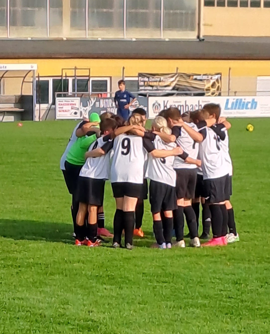 Junge Fußballspieler huddle auf dem Spielfeld, um Strategien zu besprechen und sich gegenseitig zu motivieren.
